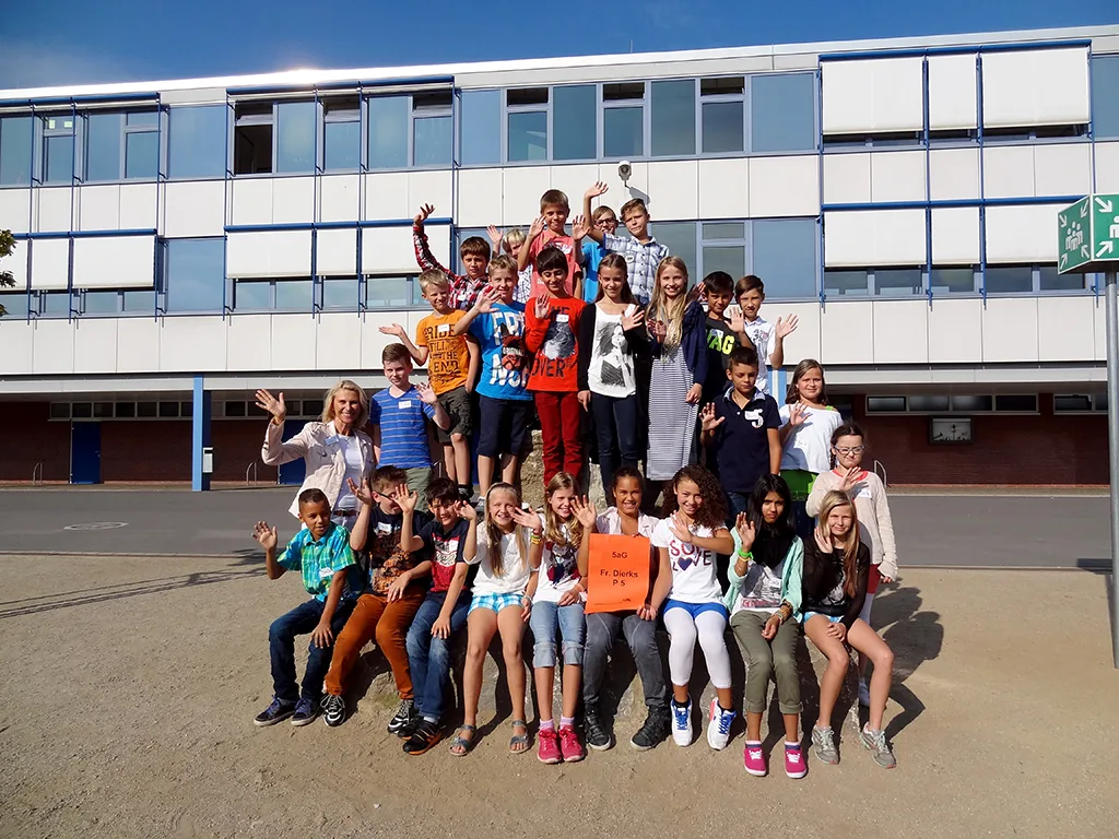 Klassenfoto einer neuen fünften Klasse, die Kinder winken.